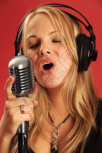 女士照片中一位美丽的金发年轻女孩戴耳机并歌唱在古老的麦克风里娱乐一种声音的高清图片素材