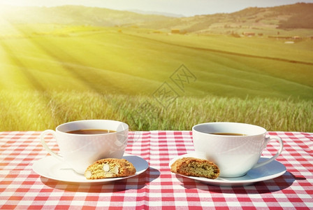 绿色面包与意大利图斯卡风景对抗的彩布上咖啡和坎通尼农场图片