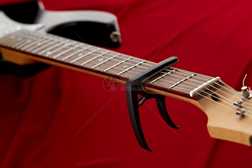 配有卡波达斯特写红色背景没有人弦乐器电声子音乐舞台会设备配有卡波达斯特的电吉他壁炉特写棕色的爵士乐蝾螈图片