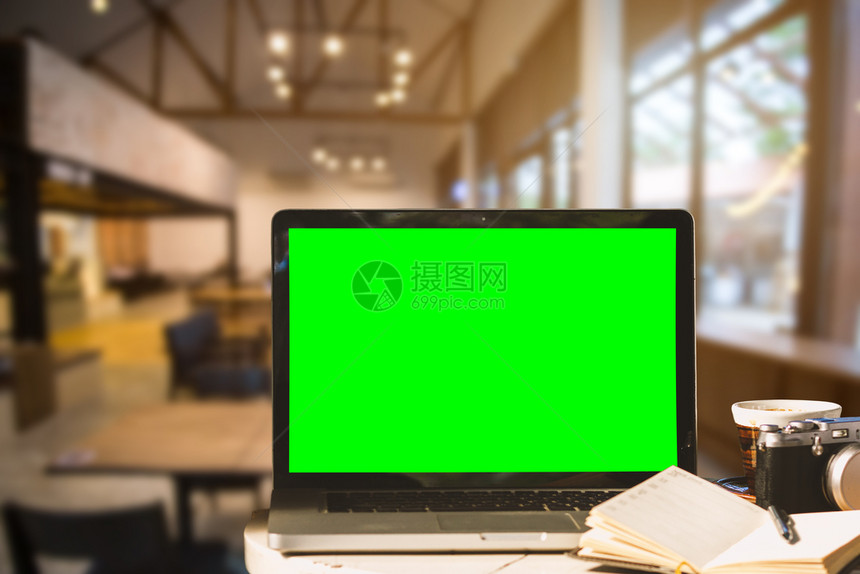 数字的木制用相机笔记本和咖啡店背景的木制桌子上咖啡杯用空白绿色屏幕拍摄笔记本电脑白色的图片