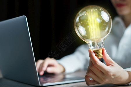 笔记本电脑灯泡使用计算机膝上型电脑和手持灯泡概念的妇女键盘图片