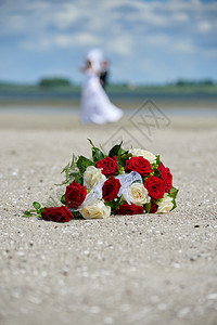 婚礼花束和一对夫妇在海滩上婚姻洋白色的图片