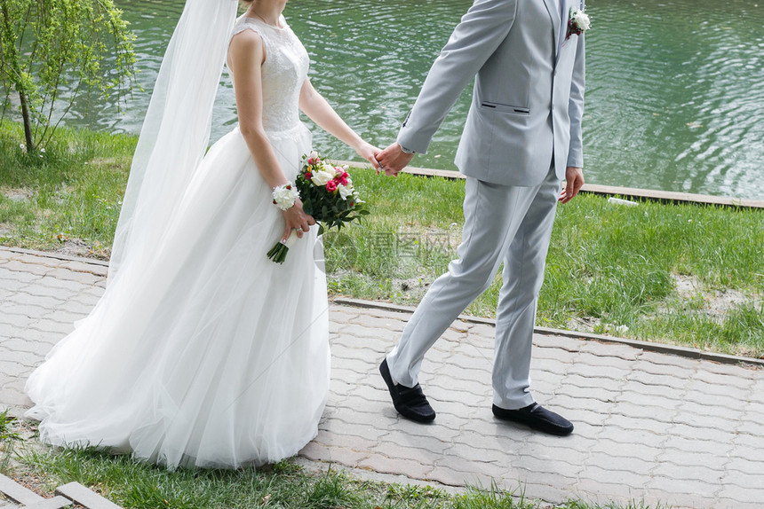 白种人现代新婚夫妇的近亲在公园一起走里他们婚礼那天与花束相伴的湖边背景上妻子男图片