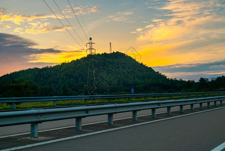高速公路上美丽的边风景山后太阳升起通向山顶高塔的铁丝网日出运输阳光图片