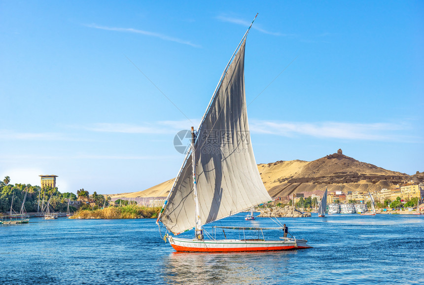 城市在尼罗河的Aswan乘帆船在阳光明媚的日落时航船在Aswan沙漠景观图片