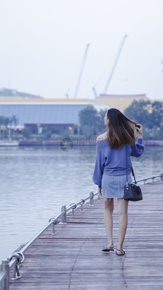 背部妇女在木桥上行走孤独自的图片