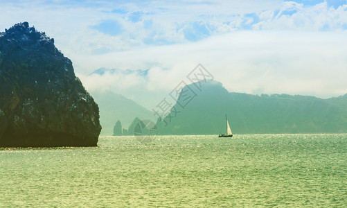旅游在雾海和岩石背景的游艇上航行海洋冒险图片