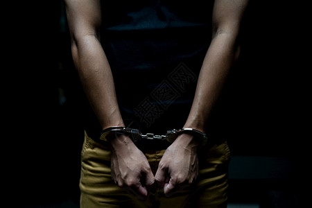 拘留贼犯罪一名囚被铐上手男囚犯在黑暗的监狱中被铐上手背景图片