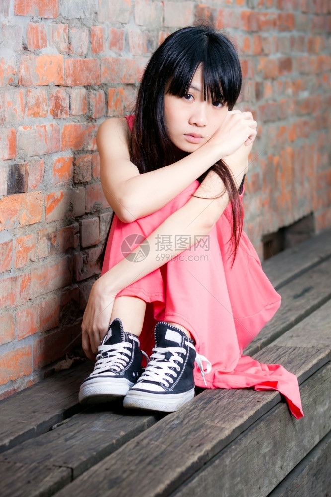 年轻的坐在红砖墙边年轻亚洲妇女感到沮丧和悲伤郁闷降低图片