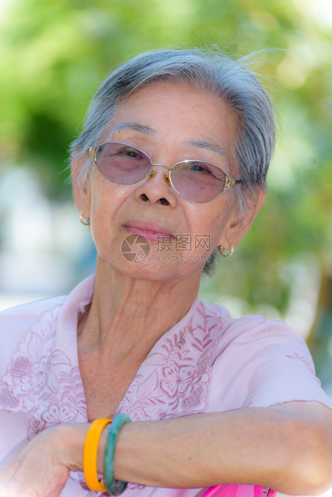 奶眼镜身穿泰国式衣服的亚洲老人在公园户外放松的肖光老妇人微笑着美丽的老年妇女快乐肖像她的脸部被近距离拍到头部摄闲暇图片