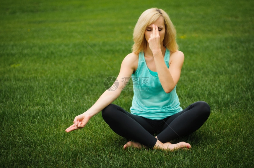 绿草的金子女人做瑜伽冥想金发公园幸福图片