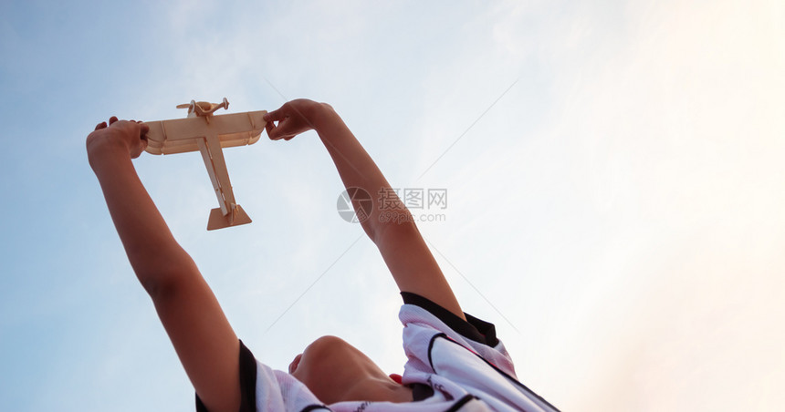 航班快乐的孩子玩木具飞机在日落的天空背景上风镜游戏图片