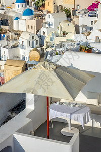 桌子希腊日落之圣托里尼岛卡路德拉的希腊太阳日光天在户外露阳台服务表上的光保护伞下在一个大型太阳伞下夏天火山口背景图片