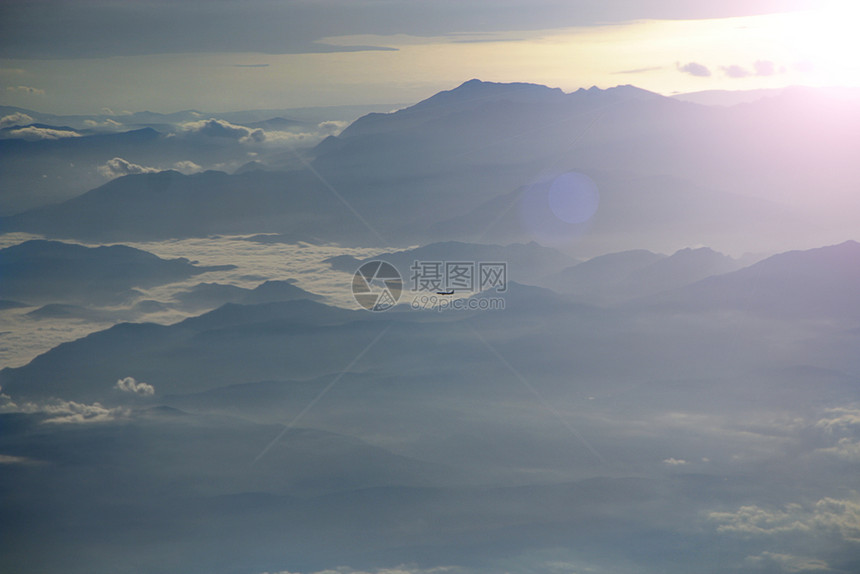 高度从飞机窗看美丽的景色从飞机窗看另一架在阳光明媚的线下飞越云层和山脉超过蓬松的图片