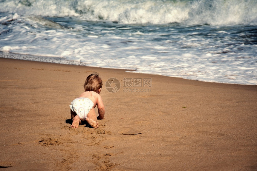 婴儿男孩在海滩上爬图片