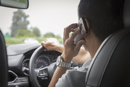 男子驾驶汽车时使用手机说话的人男驾驶汽车镜子里面沟通路高清图片素材