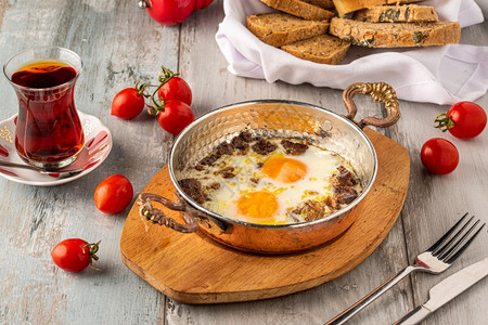 木制的厨师土耳其鸡蛋炒和铜锅中的烤肉炖图片