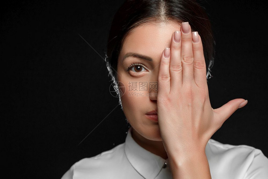 沮丧隐藏一个亚洲黑发女人的肖像穿着白衬衫用她的手在黑色背景上蒙住她的脸覆盖图片