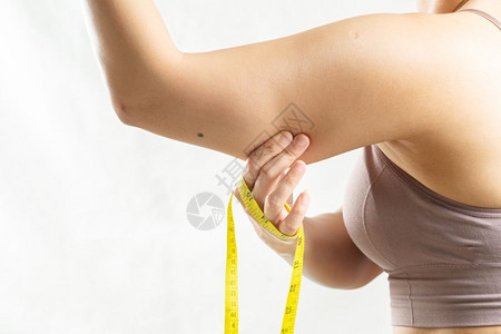 超重人们皮肤女用测量胶带捏着她过度脂肪的手臂妇女饮食生活方式的概念注图片