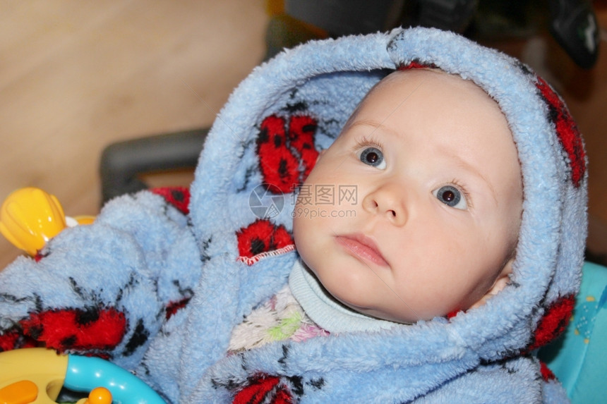 童年小宝穿着蓝色的睡袍躺在床上的可爱小婴儿与惊异的目光摆姿势美丽图片
