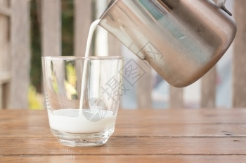 进入巴氏杀菌从一个投手倒牛奶到玻璃杯股票照片奶油图片