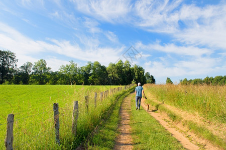 阳光男人在法国新华利州绿山的风景中走着狗行车道欧舒丹图片