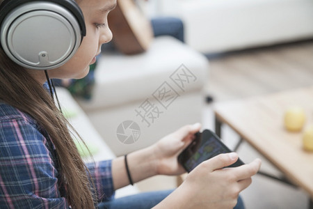视频乐趣家玩游戏智能手机的女孩耳快乐的高清图片素材