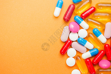 健康药店橙色背景上的什锦药丸片剂和胶囊瓶子复制文本空间头痛图片