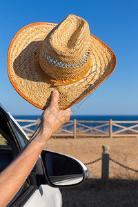 支撑车窗中的手臂在海岸和边展示夏帽稻草季节高清图片