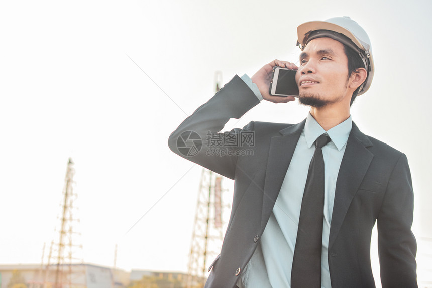 建筑工地的商人打电话手机或移动智能电话在施工地联系下面聪明的
