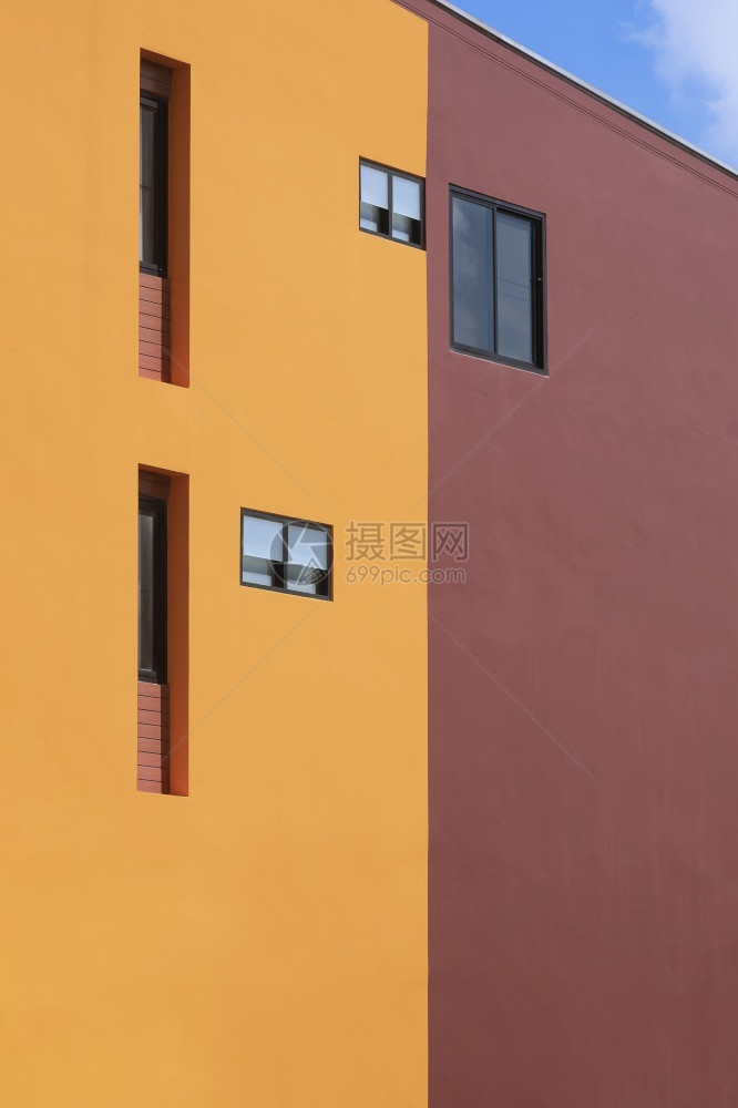 橙色和棕褐现代建筑墙上各种固定玻璃窗的背景在视野侧图和垂直框中蓝天空以及城市建造屋图片