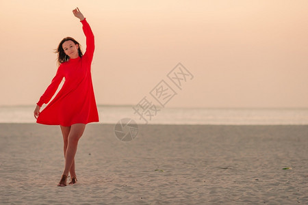 请享用海滨夕阳下白沙滩上的美丽女人夕阳下白沙滩上可爱快乐的小女孩红色图片