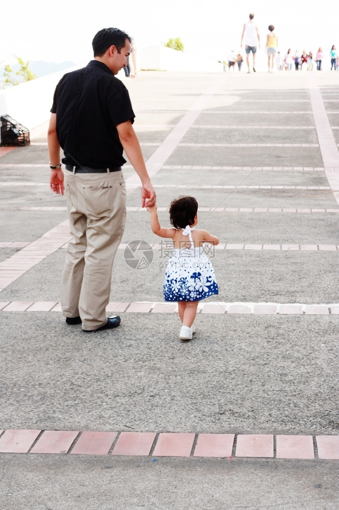 父亲牵着小女孩的手走在街上图片
