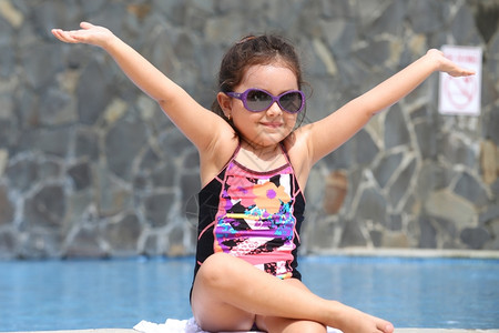 快乐的小女孩在泳池外张开双臂图片