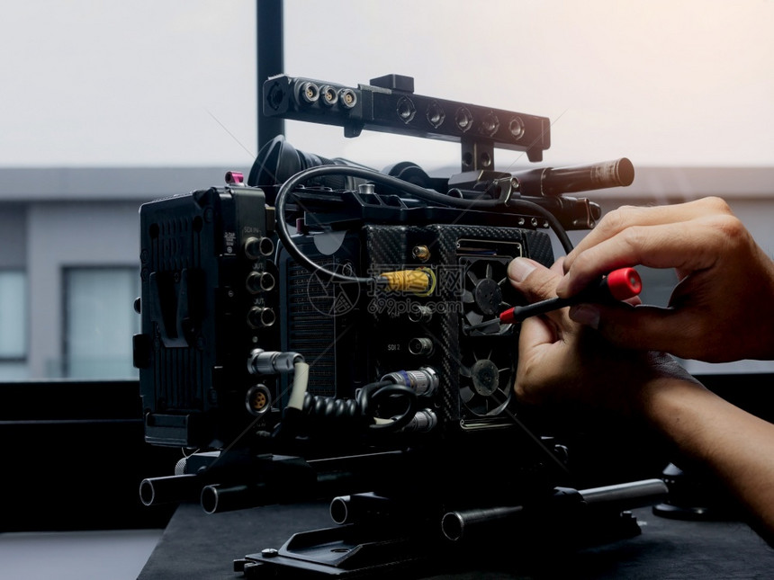 镜片技术员用螺丝起子换电影摄机的冷却风扇数字图片