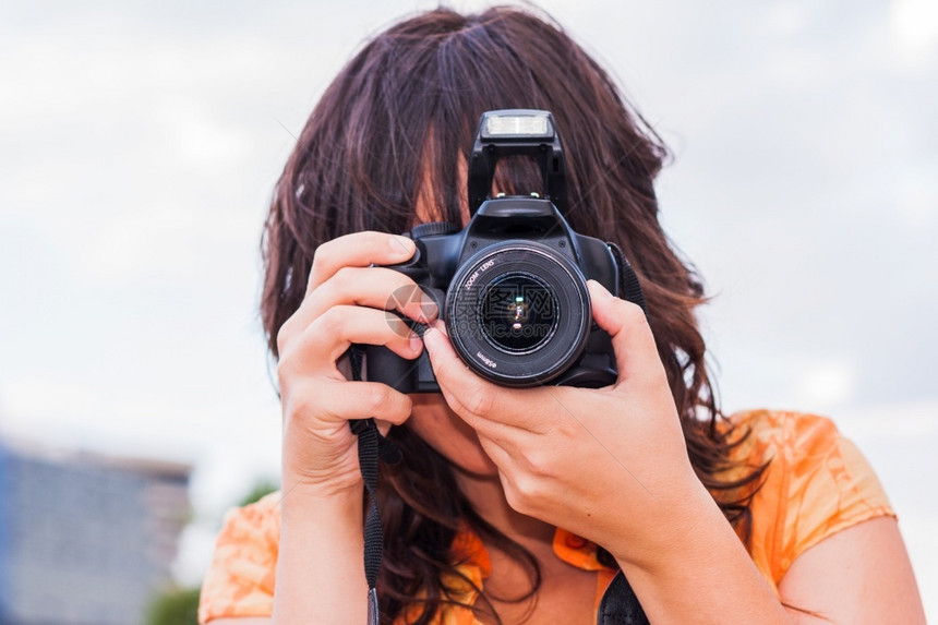 摄影师美丽的现代一个年轻女孩用反射照相机拍图片