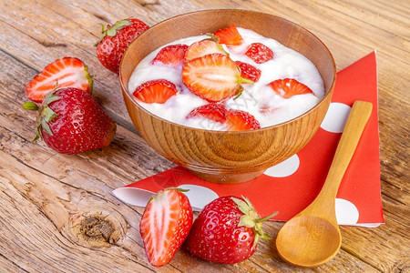新鲜的草莓酸奶和木本底碗中的草莓酸奶水果图片