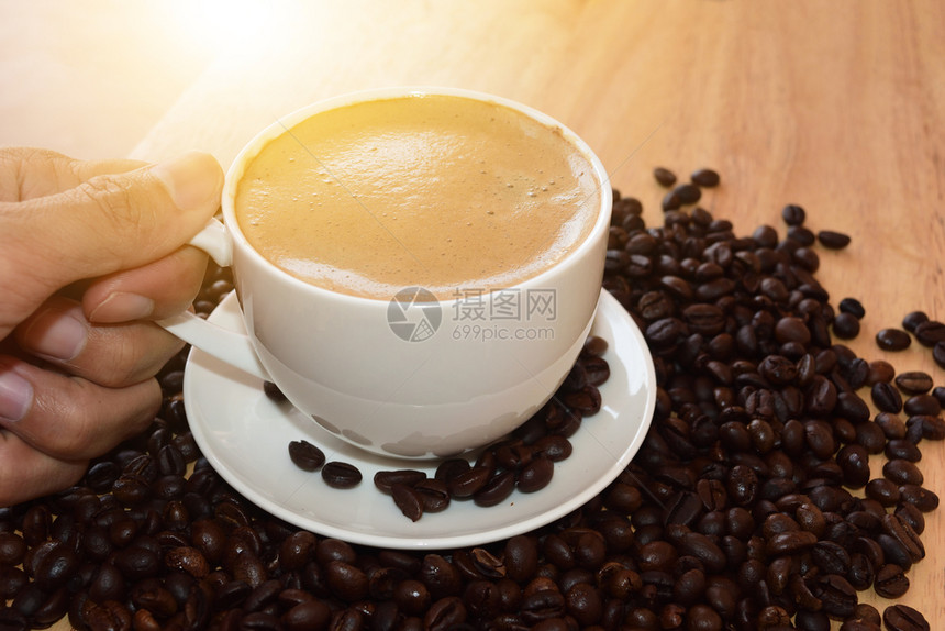 粮食持咖啡杯的人喝着桌上咖啡和豆的马克杯白色的图片