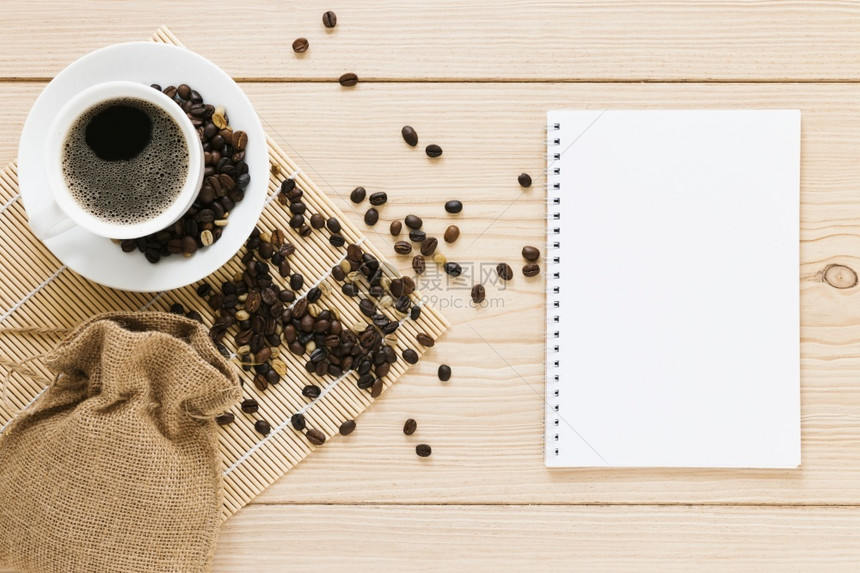 咖啡豆旁的空白笔记本图片
