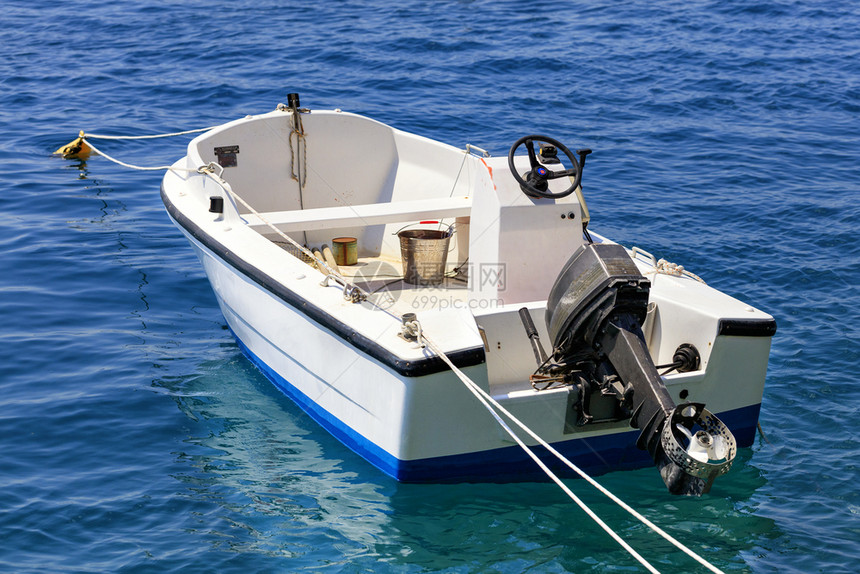 木板地中海希腊语一艘渔船停泊在爱奥尼亚海的清澈绿水中有一辆高架发动机Loutraki希腊一艘机动船停泊在爱奥尼亚海的清阔水域图片