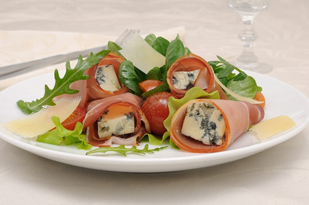 小吃美味的开胃菜卷果酱蓝奶酪在混合生菜和干酪切片蔬图片