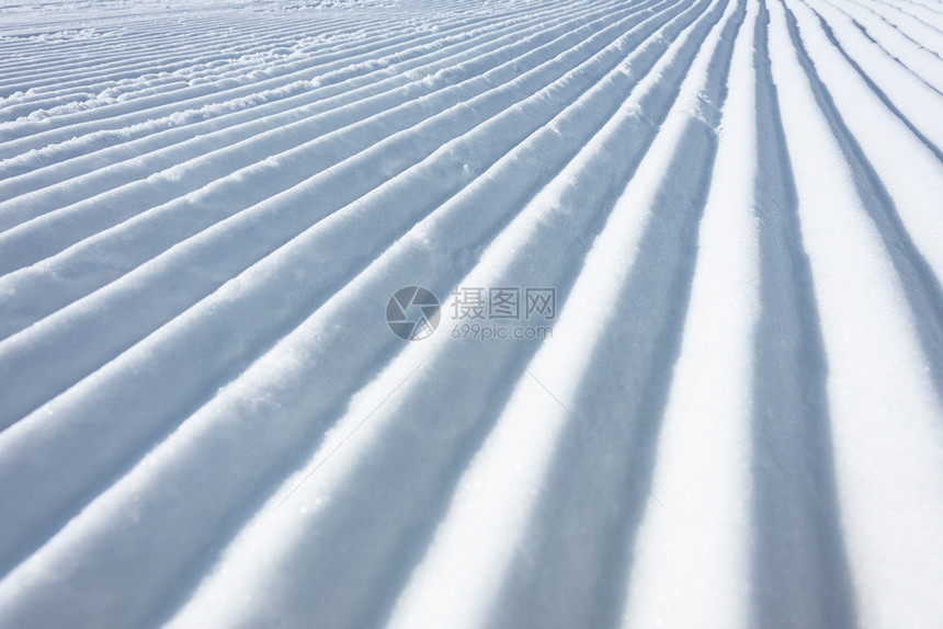 阿尔卑斯山采取美容师滑雪猫作为纹理背景所留下的滑雪斜坡上几何轨道线图片