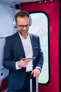 商业男人在将电影从移动话流到无线耳机列成火车上站得住脚内容图片