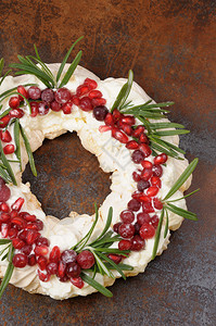 烘烤甜点蔓越莓圣诞花环由奶油石榴红莓玫瑰特饰的蛋白瓜制成背景图片