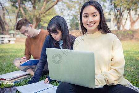 坐在绿色草地上一起学习的学生们高清图片