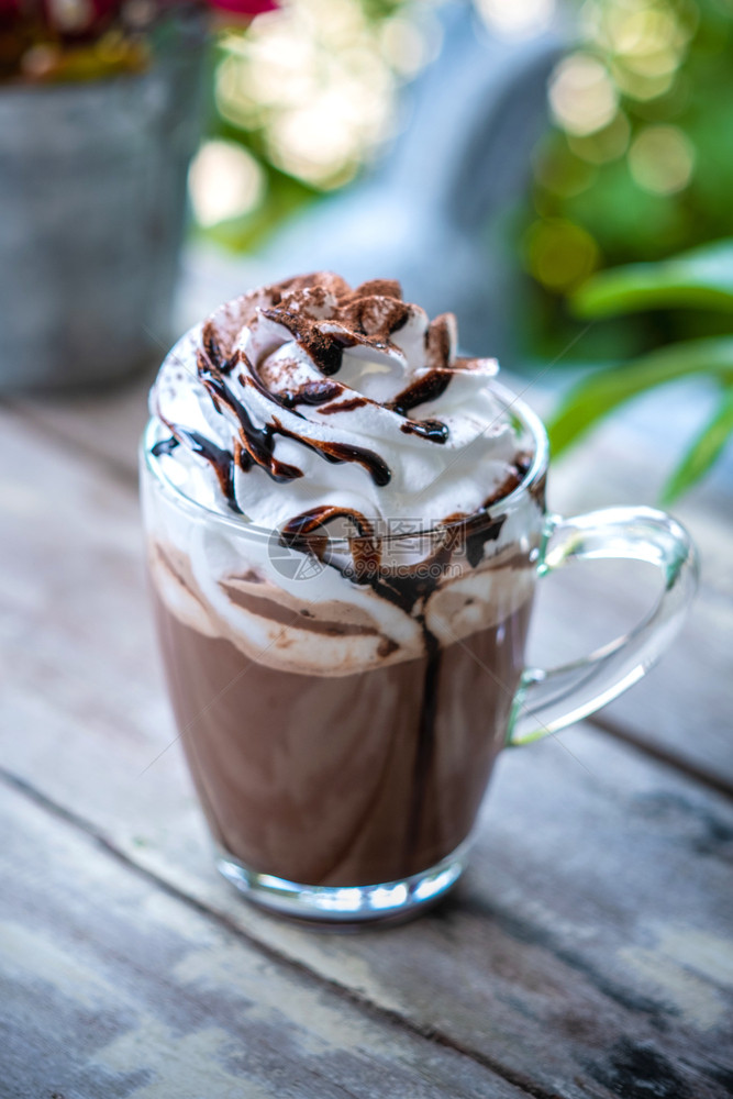 咖啡杯中的热巧克力可木背上有奶油和鲜摩丝温暖的马克杯图片