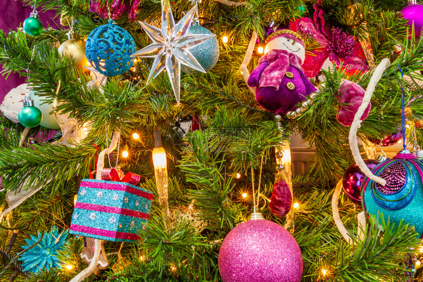 圣诞树装饰着紫色主题明星礼物紫雪人装饰球和蜡烛灯都亮着传统的帕利卡拉斯火花图片