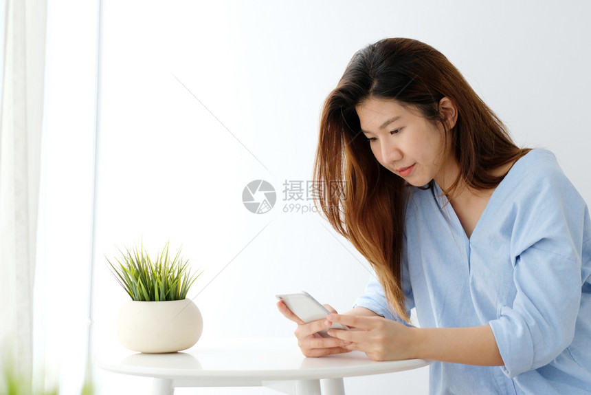 成人技术房间年轻亚洲女使用智能手机微笑快乐和放松的情绪在白室背景中电话上的人生活方式图片