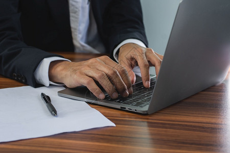 数字的办公室内使用电脑键盘上网搜索手打字的男子家笔记本电脑图片
