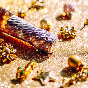有创造力的魅圣诞或新年配有一瓶玫瑰香槟和金色闪亮背景的花彩装饰喜庆布基和影子的侧观以及庆祝党的创造概念以庆祝圣诞节或新年闪光背景图片